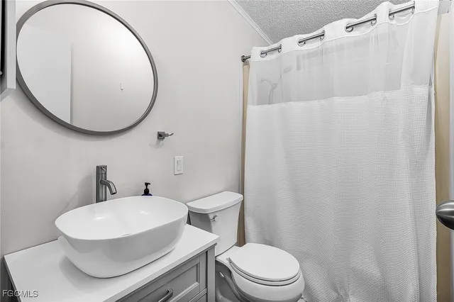 a white toilet sitting next to a bathroom sink and a mirror