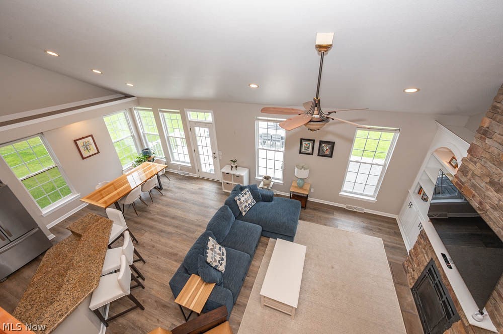 6787 South Palmyra Road Canfield, OH 44406 - Photo 15 of 30 Open-concept living space featuring wood-finish flooring, a stone-faced fireplace with hearth, and a vaulted ceiling with recessed lighting