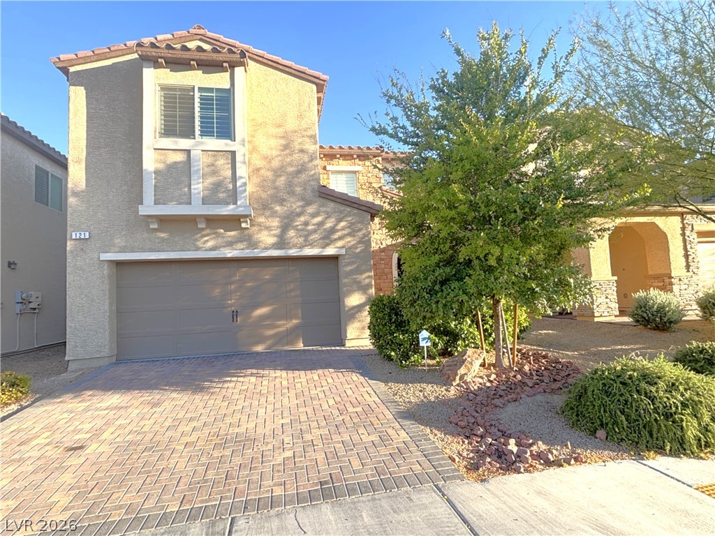121 Elm Reed Avenue Las Vegas, NV 89113 - Photo 1 of 30 A Mediterranean-style facade welcomes you, featuring an integrated garage and a decorative paved driveway.