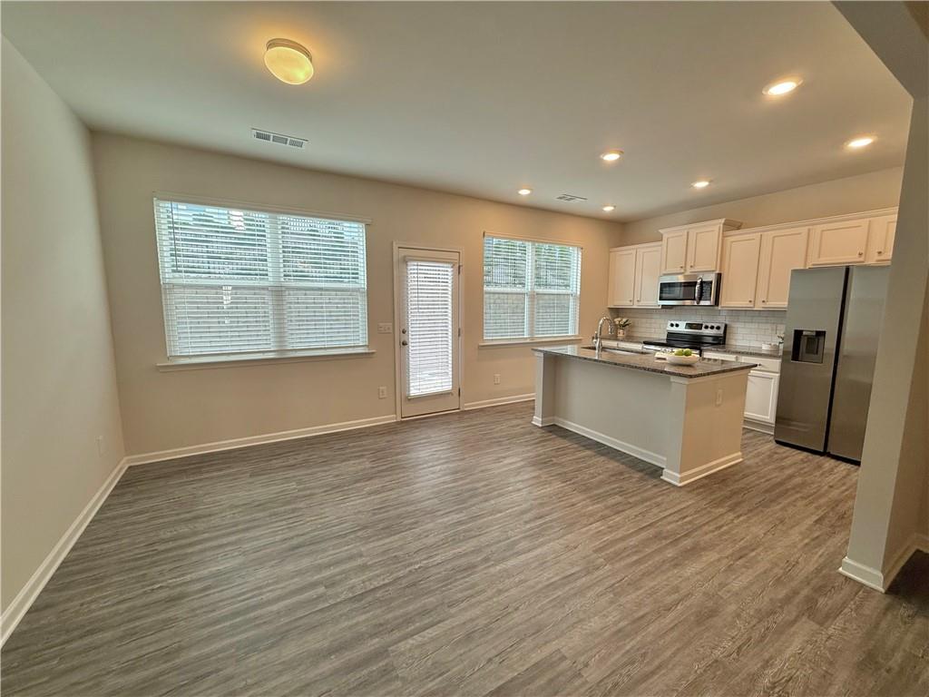 276 Whitetail Circle Canton, GA 30115 - Photo 10 of 40 a kitchen with stainless steel appliances granite countertop a stove a sink dishwasher a refrigerator and white cabinets with wooden floor