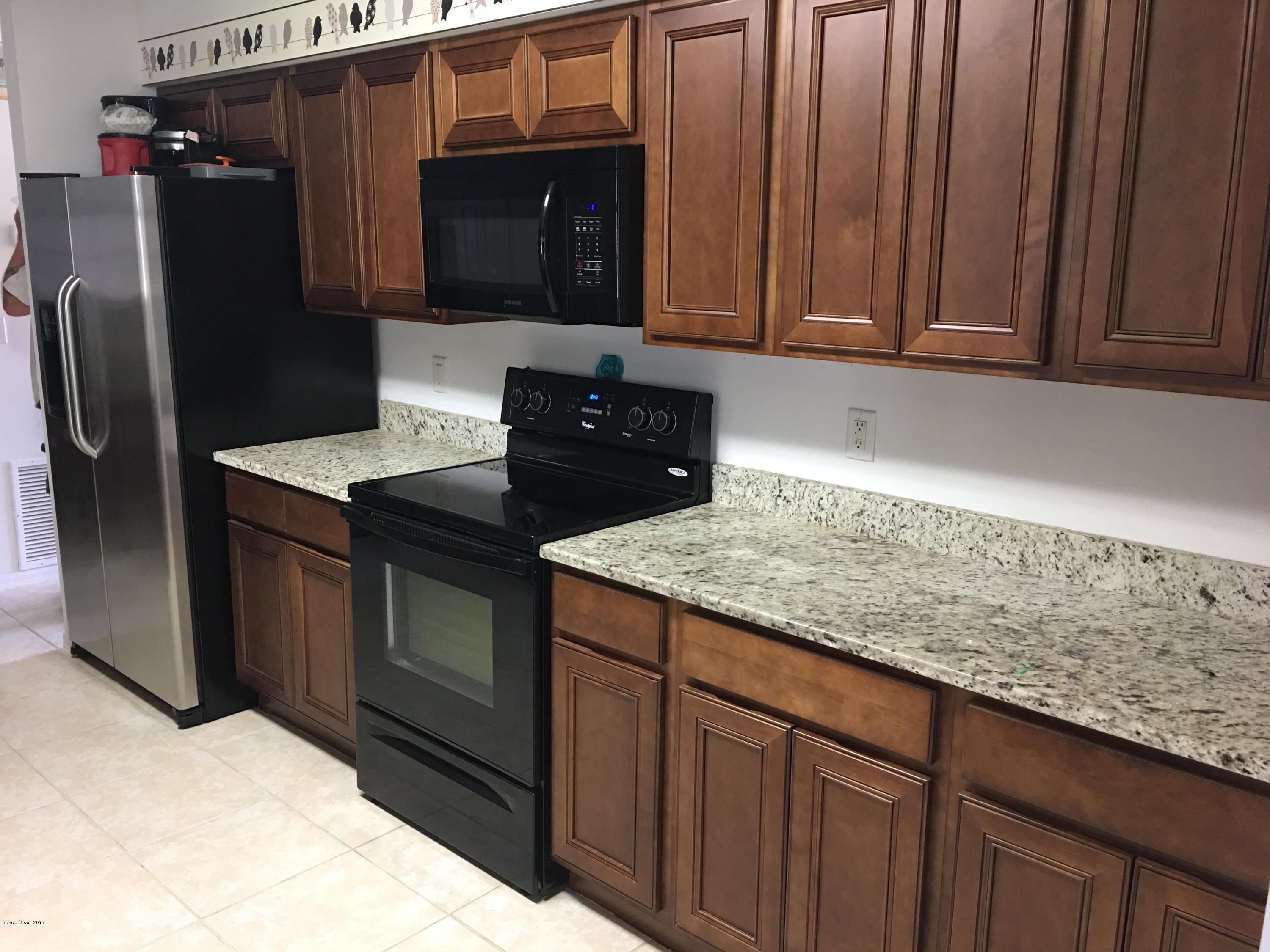 853 Furth Road Northwest Palm Bay, FL 32907 - Photo 2 of 29 a kitchen with granite countertop wooden cabinets and refrigerator