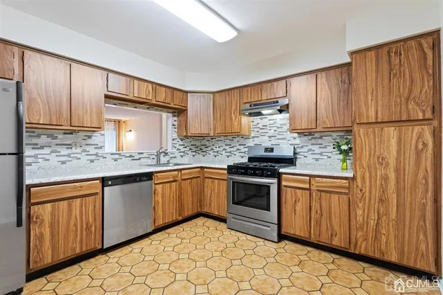 a kitchen with granite countertop a sink stainless steel appliances and cabinets
