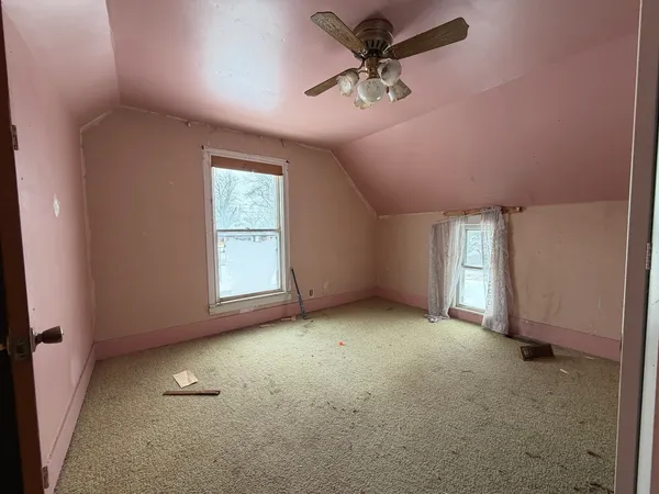 an empty room with windows and fan