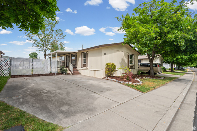 1025 North 300 West, Unit 97 Springville, UT 84663 - Photo 1 of 1 Light-colored exterior featuring a covered porch with steps, a concrete driveway, and a landscaped front yard with mature trees