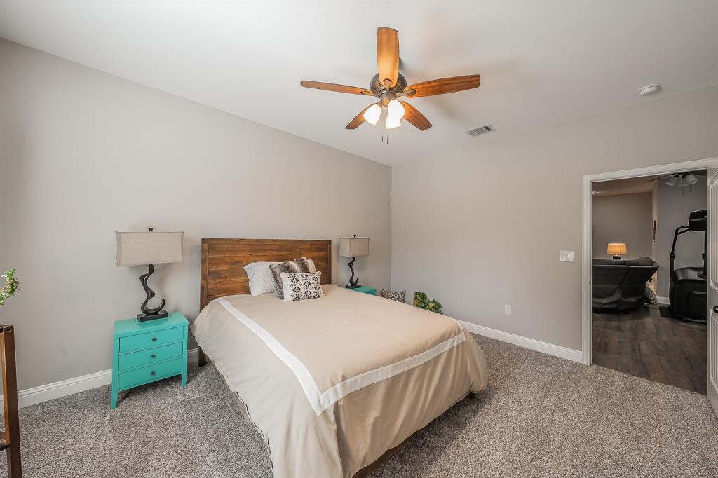 117 Rock Salt Drive Springtown, TX 76082 - Photo 21 of 38 Carpeted room featuring a wood-finish bed frame and a ceiling fan with integrated lighting