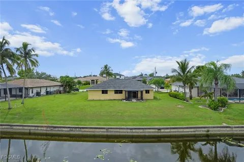 a view of a big house with a big yard plants and large trees
