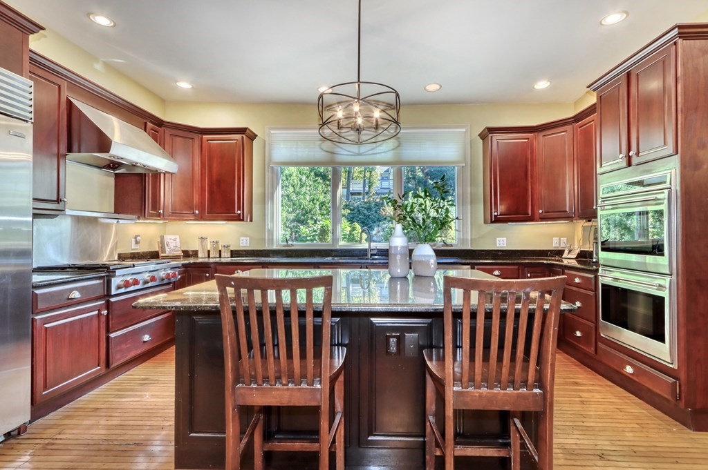 5 Chestnut Street Melrose, MA 02176 - Photo 14 of 42 a kitchen with stainless steel appliances granite countertop a stove top oven a sink dishwasher a dining table and chairs with wooden floor