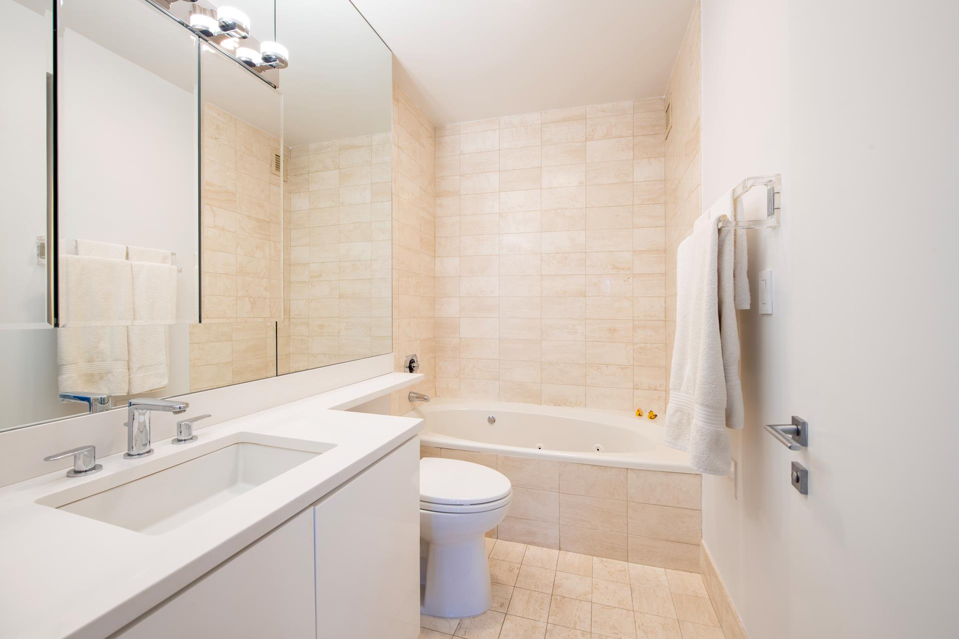 200 East 61st Street, Unit 14B Manhattan, NY 10065 - Photo 5 of 15 a bathroom with a sink toilet tub and shower