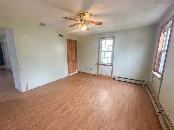 an empty room with wooden floor and fan