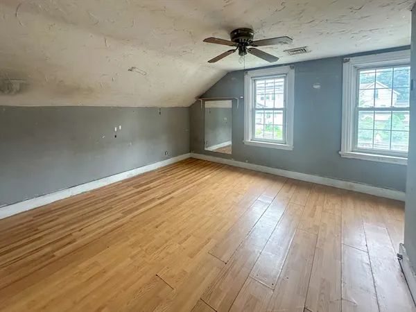 an empty room with wooden floor and windows