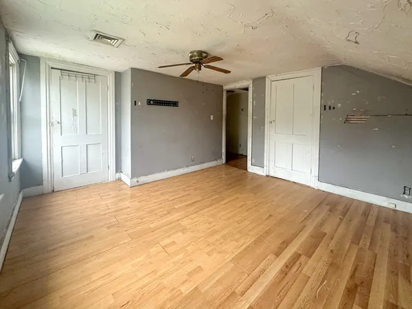 a view of empty room with wooden floor and a ceiling fan