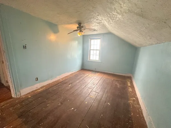 an empty room with wooden floor cabinet and windows