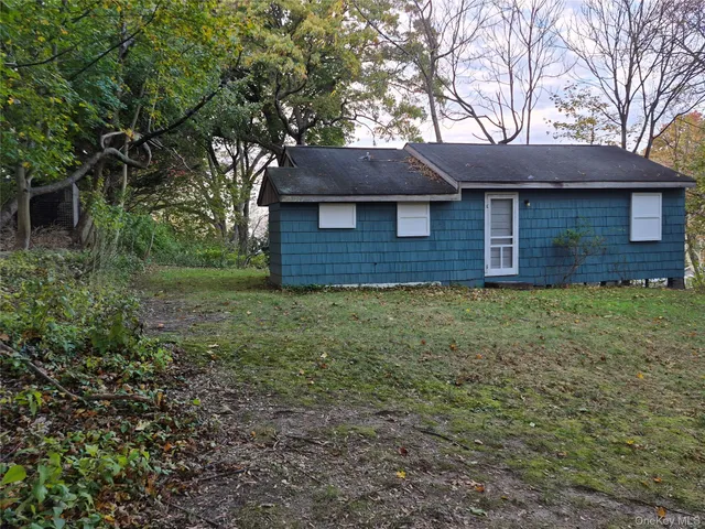 a view of a brick house next to a yard with large trees