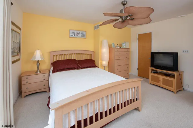 a bedroom with a bed and a flat tv screen on dresser