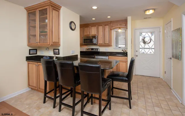 a kitchen with stainless steel appliances granite countertop a stove top oven a sink a dining table and chairs