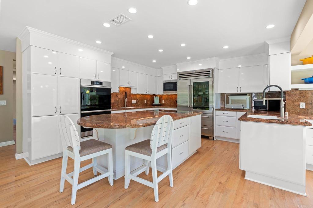 1229 Caminito Graciela Encinitas, CA 92024 - Photo 10 of 34 a kitchen with kitchen island granite countertop wooden floors stainless steel appliances and white cabinets