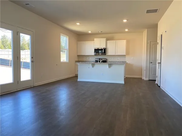 a view of kitchen with stainless steel appliances granite countertop a refrigerator a sink a stove and a wooden floors