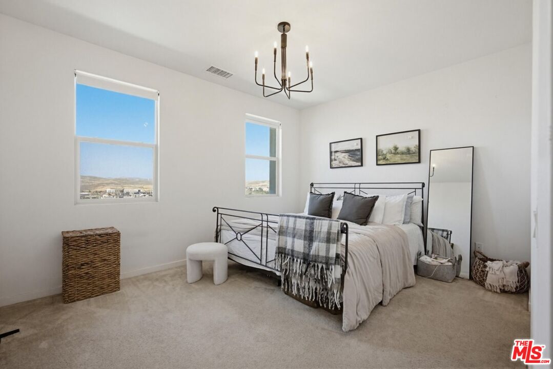 4105 Cameron Way, Unit 103 Corona, CA 92883 - Photo 15 of 30 a spacious bedroom with a bed and a chandelier