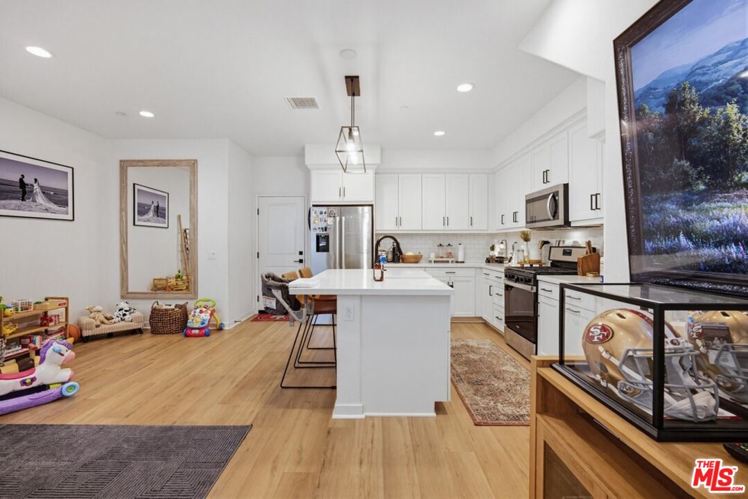 4105 Cameron Way, Unit 103 Corona, CA 92883 - Photo 6 of 30 a kitchen with a sink dishwasher stove and white cabinets with wooden floor