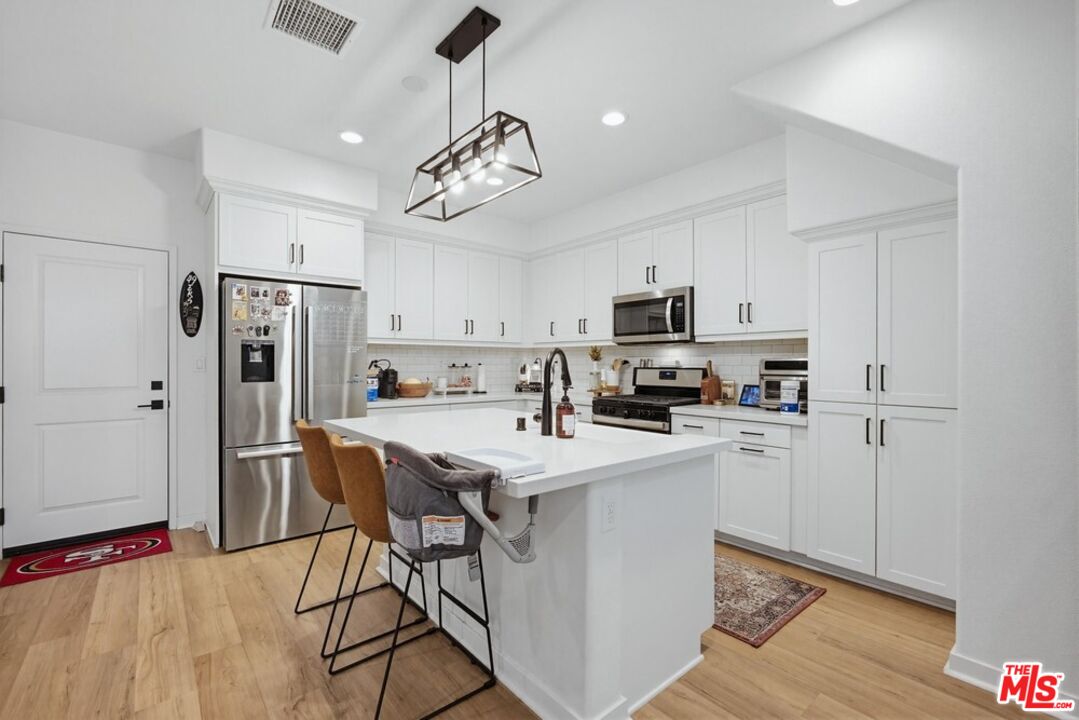 4105 Cameron Way, Unit 103 Corona, CA 92883 - Photo 7 of 30 a kitchen with stainless steel appliances a refrigerator a stove a sink a microwave and cabinets