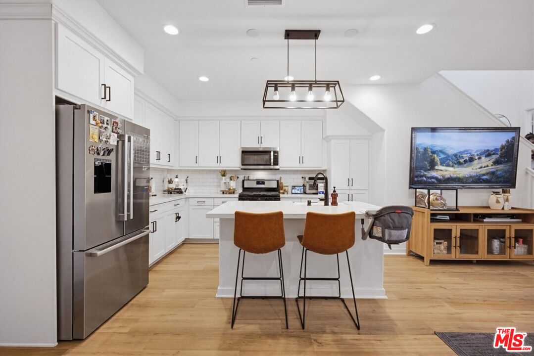 4105 Cameron Way, Unit 103 Corona, CA 92883 - Photo 8 of 30 a kitchen with stainless steel appliances granite countertop a refrigerator a stove a kitchen island a dining table and chairs with wooden floor