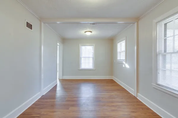 an empty room with wooden floor and windows