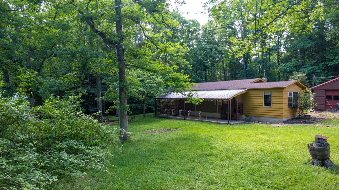 8 Cross Rds Drive Jim Thorpe, PA 18229 - Photo 27 of 32 A secluded dwelling nestled amidst mature trees, boasts a charming porch and grassy area.