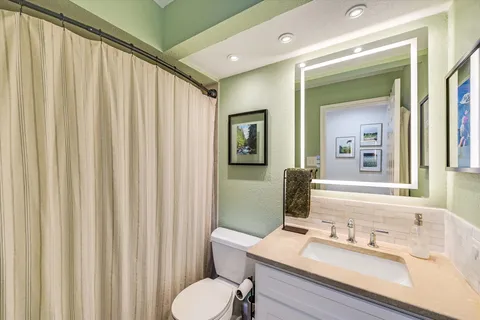 a bathroom with a sink mirror and a toilet