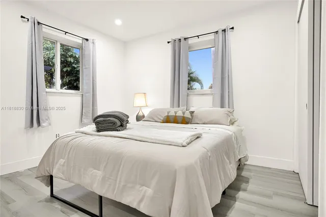 a bedroom with a bed and a large mirror next to a window