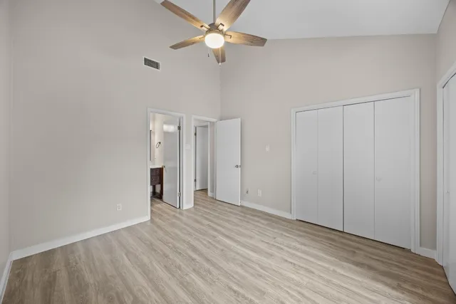 an empty room with wooden floor and ceiling fan