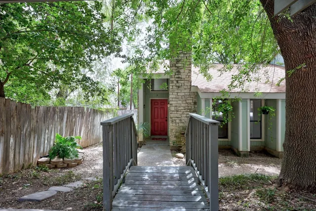 a view of a house with wooden fence and potted plants