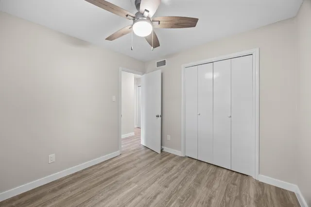 an empty room with wooden floor fan and windows