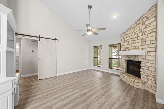 a view of an empty room with wooden floor fireplace and a window