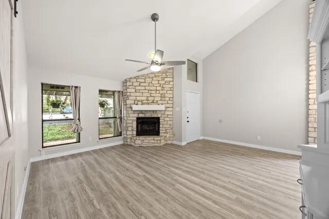 an empty room with windows fireplace and wooden floor
