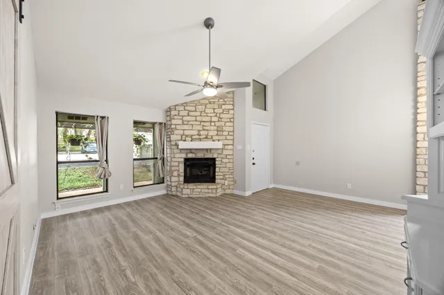 an empty room with windows fireplace and wooden floor