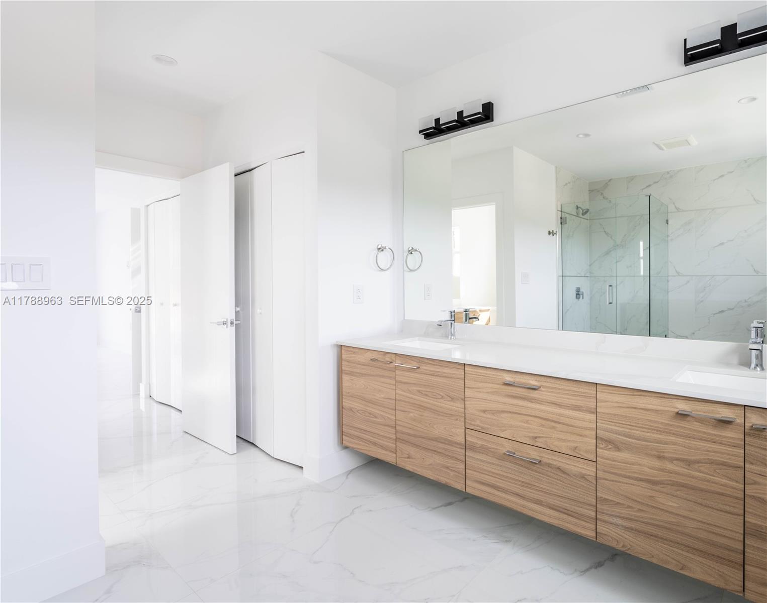 910 Southwest 24th Road Miami, FL 33129 - Photo 32 of 38 a bathroom with a double vanity sink a mirror and a shower