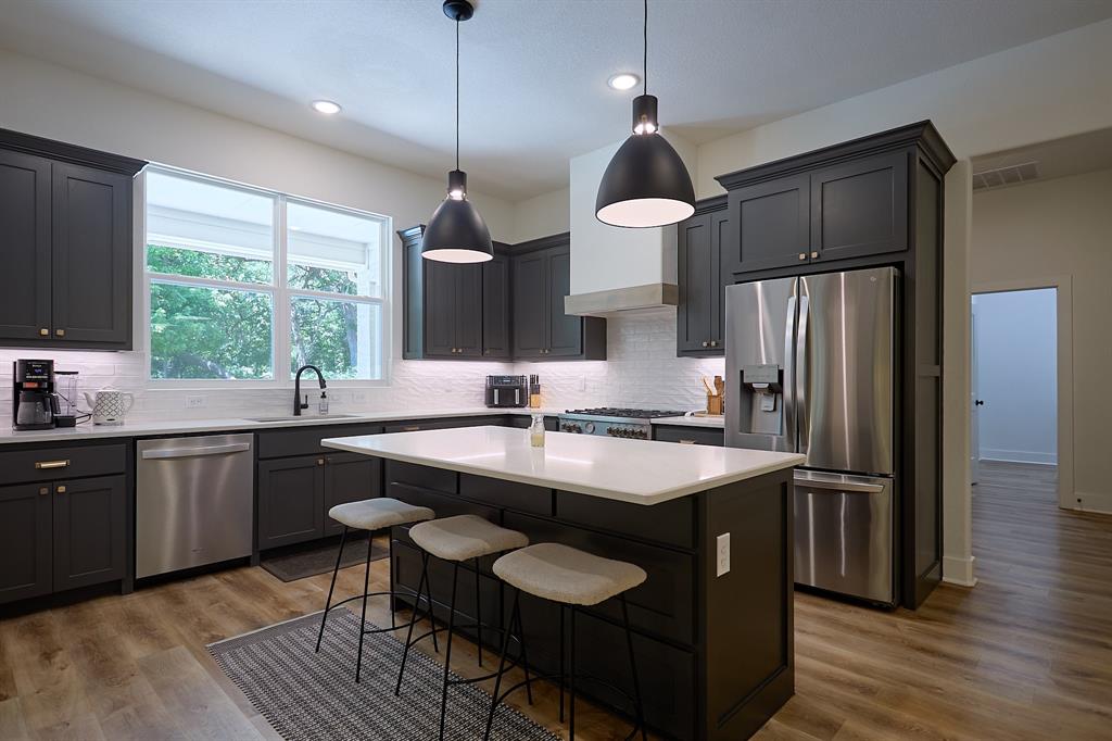 358 Glade Valley Road Azle, TX 76020 - Photo 7 of 35 Modern kitchen featuring dark cabinetry, white countertops, stainless steel appliances, a tile backsplash, and wood-finish flooring