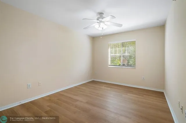 an empty room with windows and chandelier fan