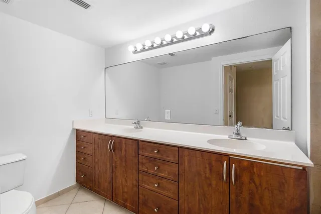 a bathroom with a granite countertop sink a toilet and a mirror