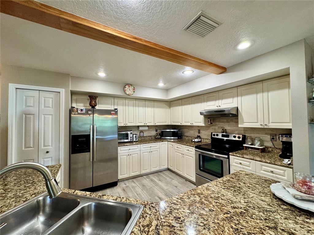1116 Sunset Point Road, Unit 202 Clearwater, FL 33755 - Photo 12 of 31 a kitchen with stainless steel appliances granite countertop a sink stove and refrigerator