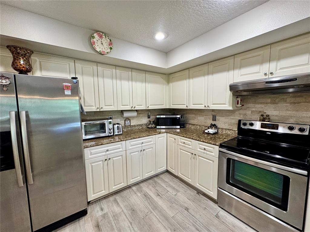 1116 Sunset Point Road, Unit 202 Clearwater, FL 33755 - Photo 13 of 31 a kitchen with stainless steel appliances granite countertop a stove a refrigerator and a microwave