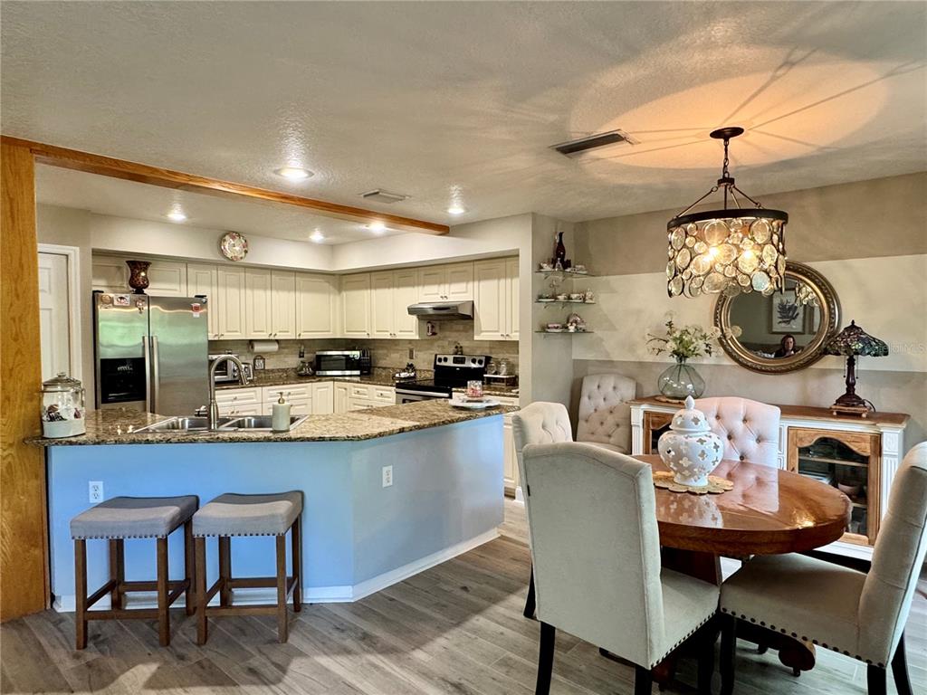 1116 Sunset Point Road, Unit 202 Clearwater, FL 33755 - Photo 8 of 31 a dining room with wooden floor a chandelier a wooden table and chairs