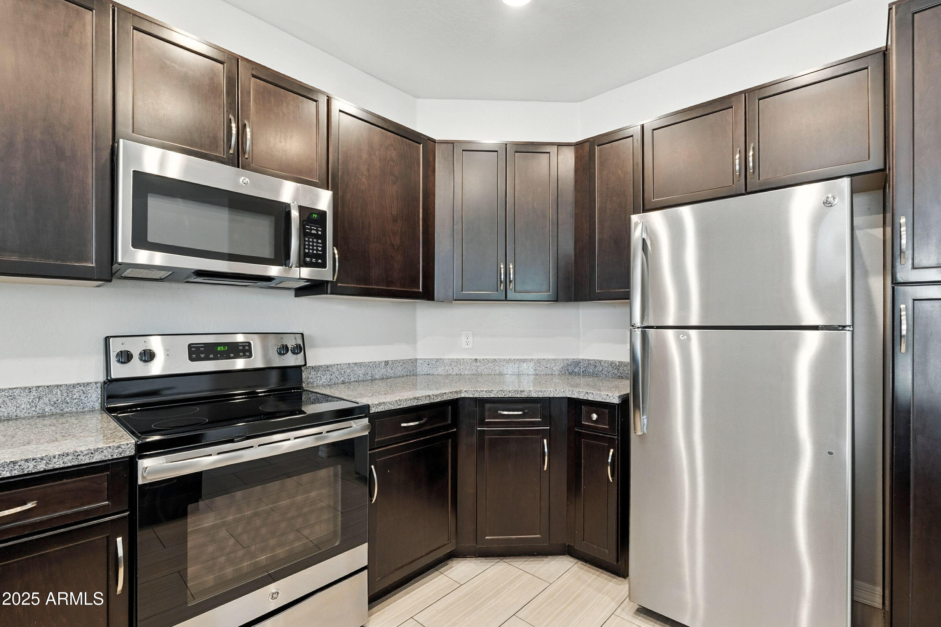 3330 South Gilbert Road, Unit 2066 Chandler, AZ 85286 - Photo 11 of 67 a kitchen with granite countertop a refrigerator and a stove top oven