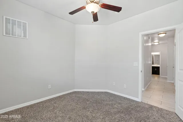 a view of an empty room and chandelier fan