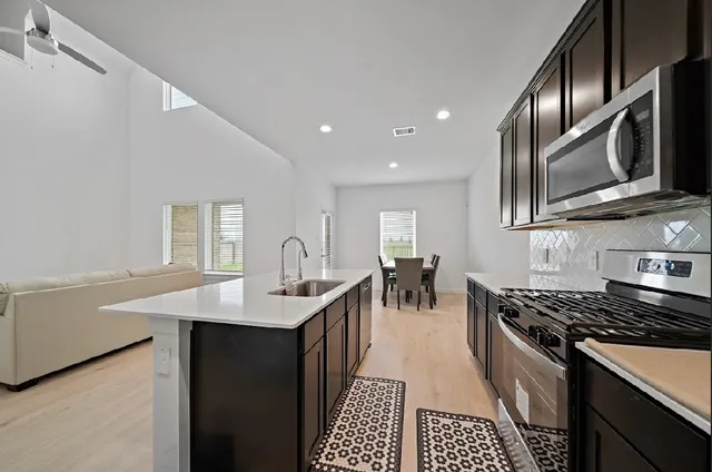 a kitchen with stainless steel appliances granite countertop a sink stove and cabinets
