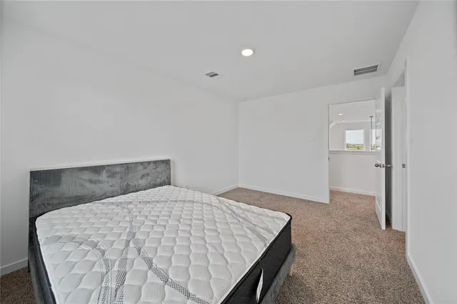 a view of a white house in front of a big yard with plants and large tree