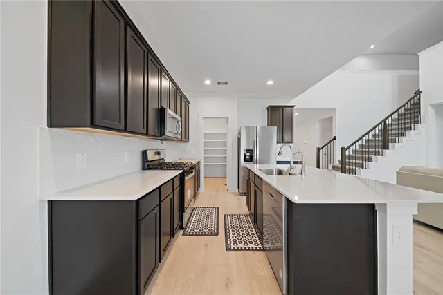 a kitchen with stainless steel appliances granite countertop a sink a stove and a refrigerator