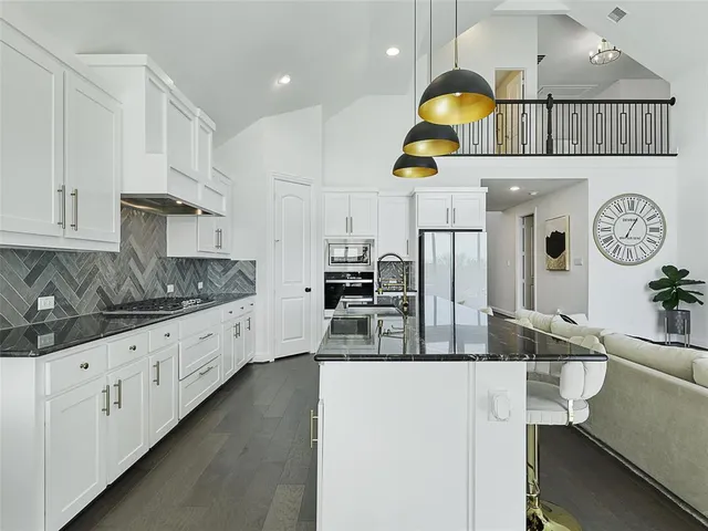 a kitchen with kitchen island granite countertop a stove a sink a oven and a dining table with wooden floor