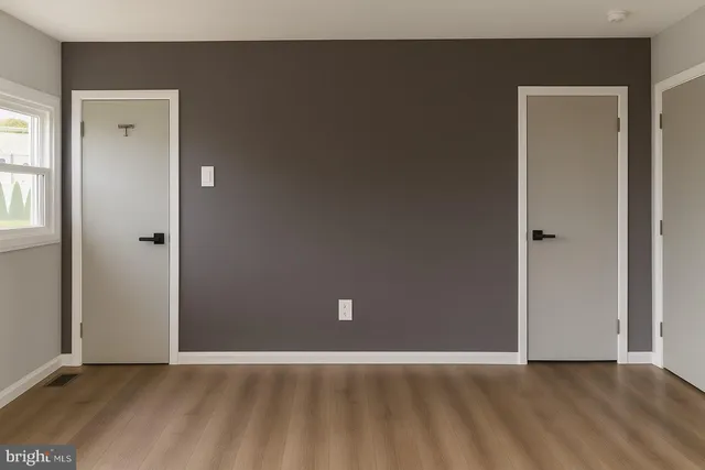 an empty room with wooden floor and windows