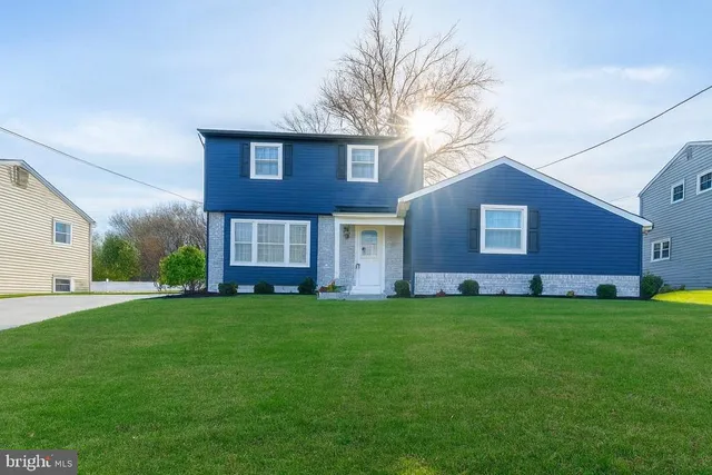 a view of a brick house with a big yard and large trees